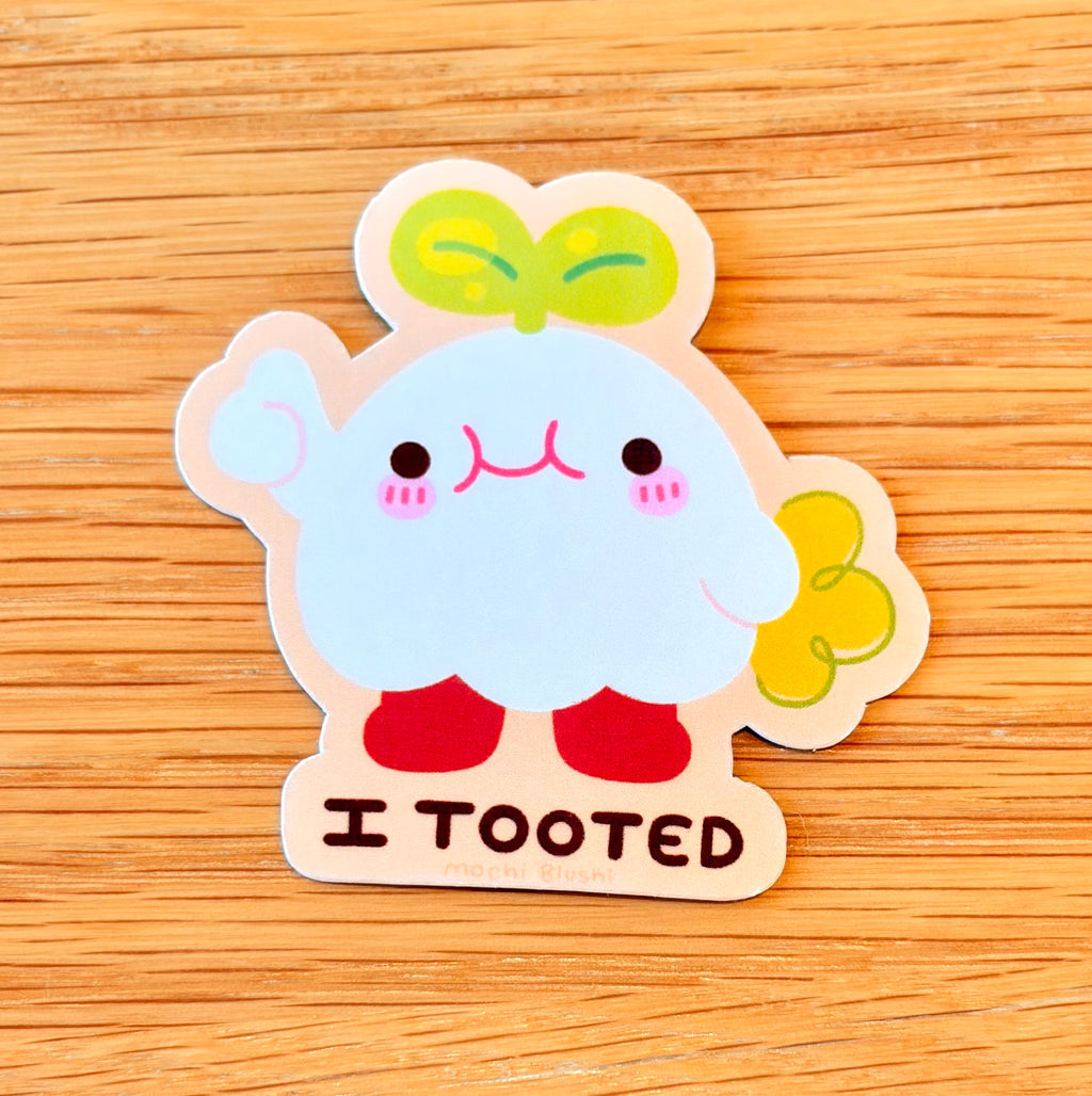 Cartoon character sticker with 'I Tooted' text on a wooden surface